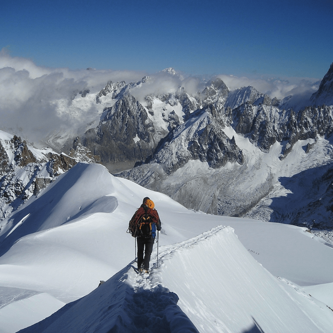 A person standing on a snowy mountain, surrounded by a majestic winter landscape.