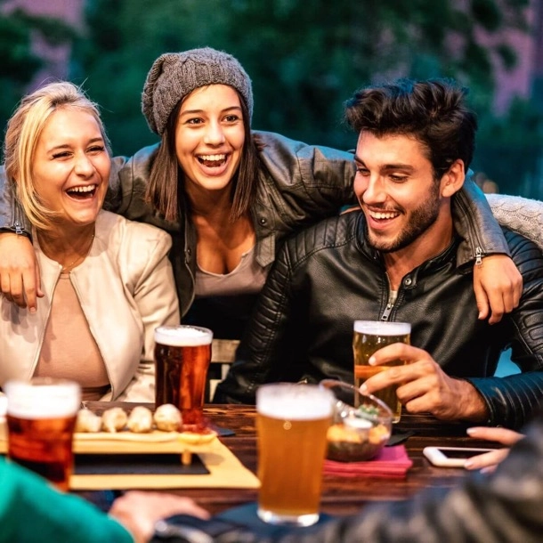 The image displays three individuals sitting at a table with beverages, possibly in a social setting. Faces are obscured for privacy. There are no math or homework problems present in the image to transcribe