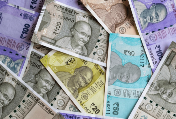 The image displays a collection of Indian currency notes in various denominations, with some areas obscured by grey rectangles. The assortment of banknotes and the concealment of certain parts could indicate a focus on currency design or security features. 