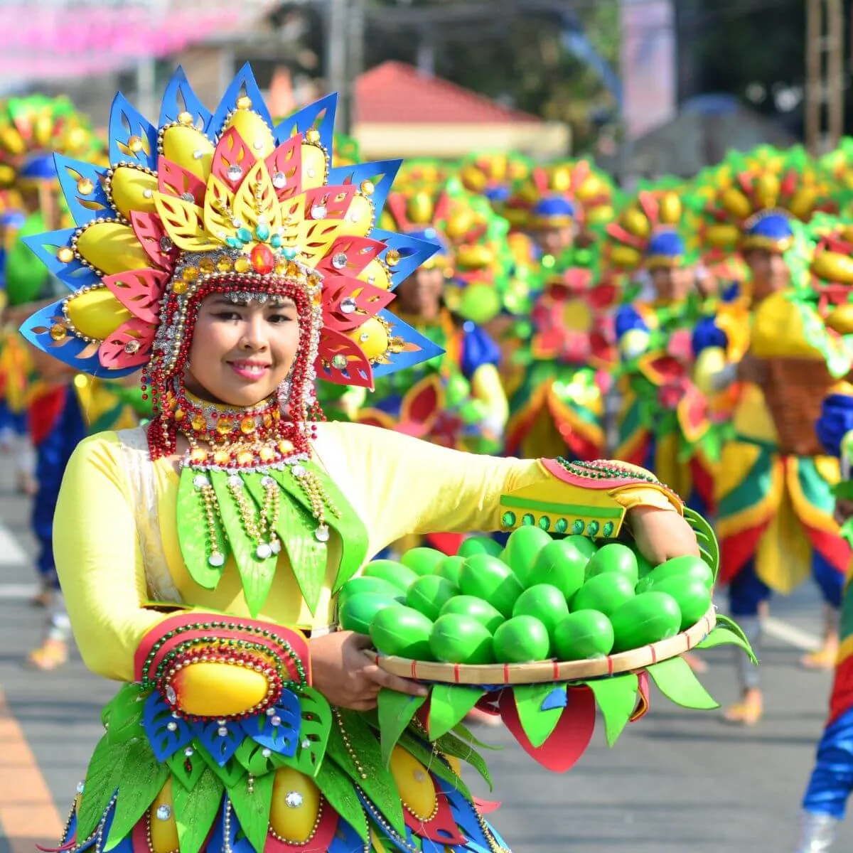 A woman in a colourful costume holds a green fruit, illustrating the richness of local culture and traditions.