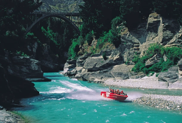 A calm river with a boat gliding peacefully along its surface, surrounded by lush greenery.